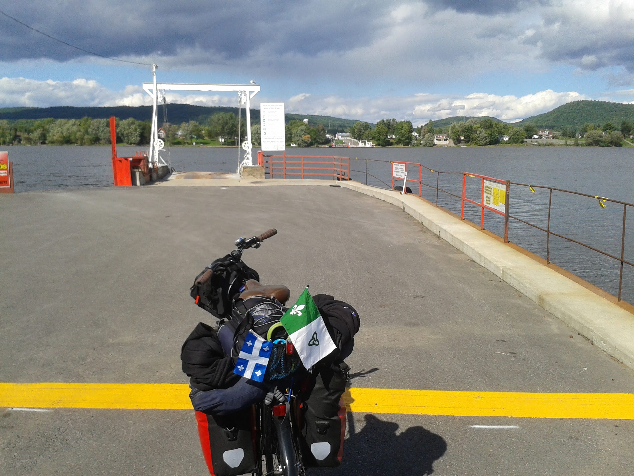 vélo chargé en cyclotourisme, avec les drapeaux du Québec et de l'Ontario français, sur un traversier