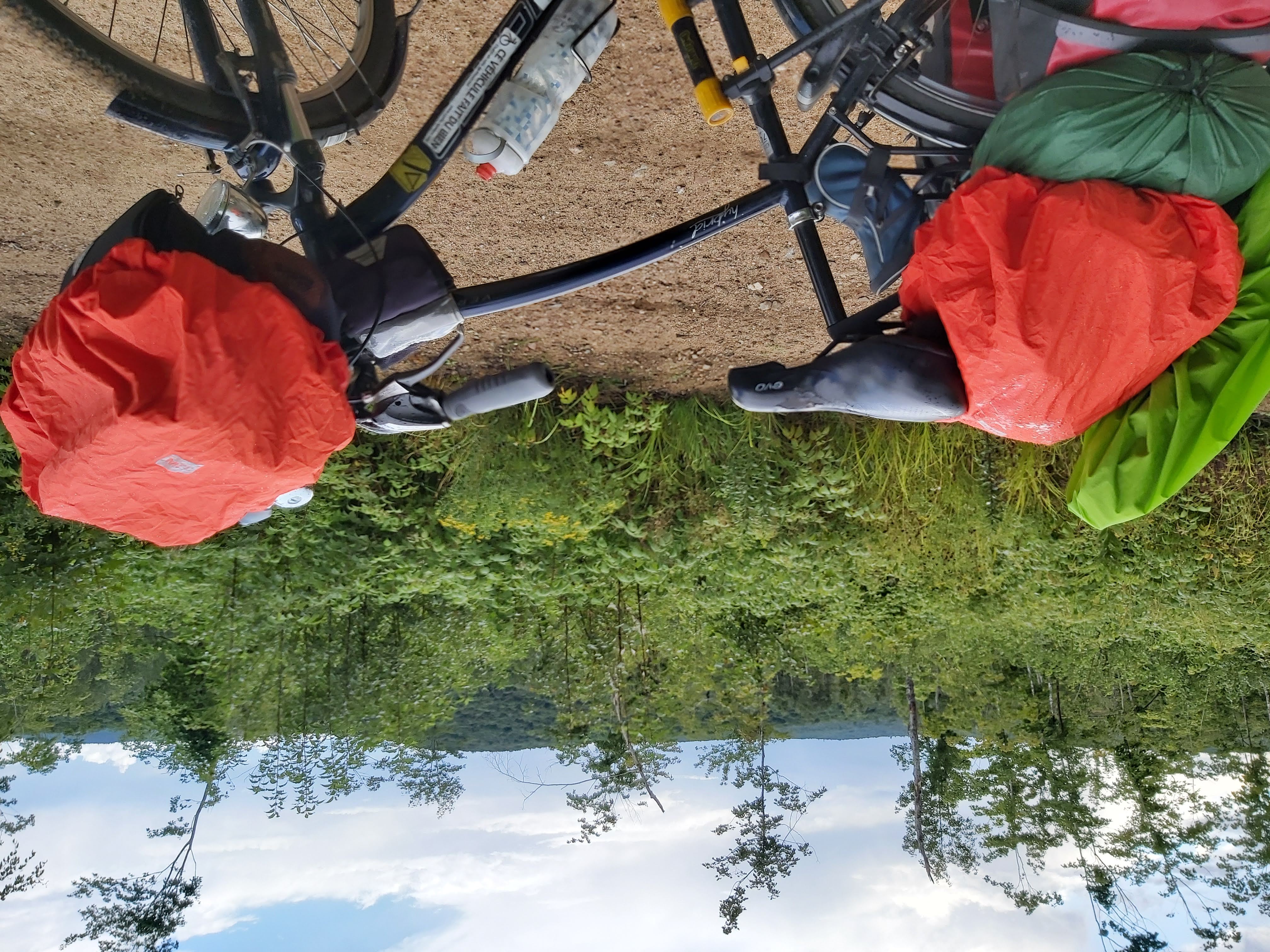 vélo chargé sur une route en gravier, ciel nuageux, végétation à côté de la route