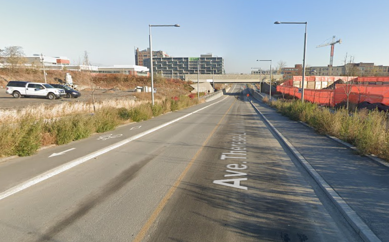 Une piste cyclable de chaque côté d'une rue près d'un terrain vague.